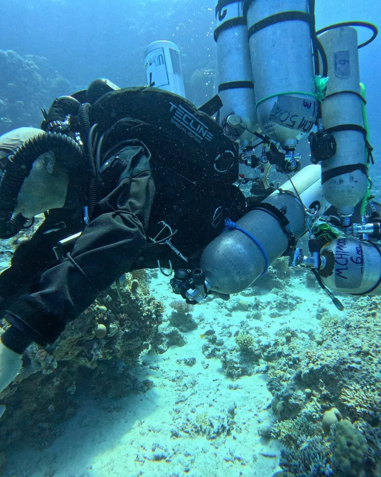 Technical diver in twinset and stage cylinders over a reef